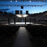 Arena em Brasília preparada para evento de MMA, com octógono e vista do Congresso Nacional ao fundo.