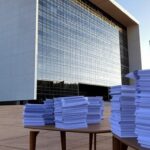 Edifício do TJDFT em Brasília com símbolos judiciais, representando julgamento de 607 mil processos e alta em audiências.