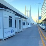 Veículos de assistência social em rua do Plano Piloto, Brasília, com monumentos ao fundo, representando operação de acolhimento.