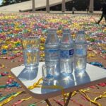 Mesa com garrafas de água e folhetos de hidratação em posto de saúde no Carnaval de Brasília 2026.