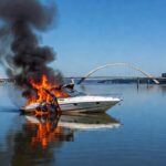 Lancha em chamas no Lago Paranoá, Brasília, com fumaça e reflexos na água, em estilo fotojornalístico.