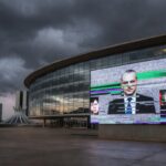 Sala de plenário vazia na CLDF com documentos espalhados e relógios parados, simbolizando atrasos em pautas urgentes.