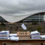 Edifício da CLDF em Brasília com documentos financeiros, representando aprovação polêmica de crédito para Ceasa sem transparência.