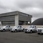 Viaturas da Polícia Civil em frente à CLDF, com documentos simbólicos de preocupações financeiras em Brasília.