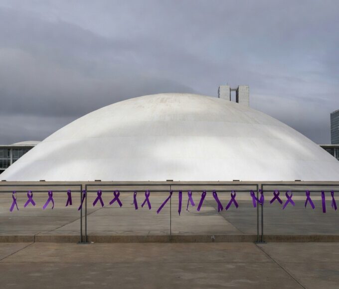 Edifício da CLDF em Brasília com fitas roxas contra violência de gênero em dia nublado.