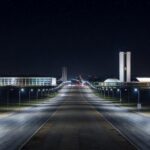 Avenida em Brasília iluminada por postes de luz LED modernos, representando modernização da iluminação pública pelo GDF e economia anual de R$ 90 milhões.