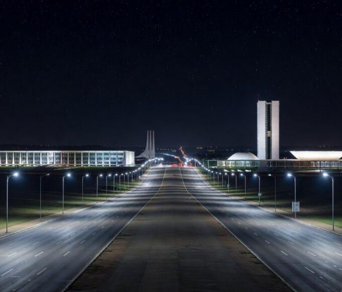 Avenida em Brasília iluminada por postes de luz LED modernos, representando modernização da iluminação pública pelo GDF e economia anual de R$ 90 milhões.